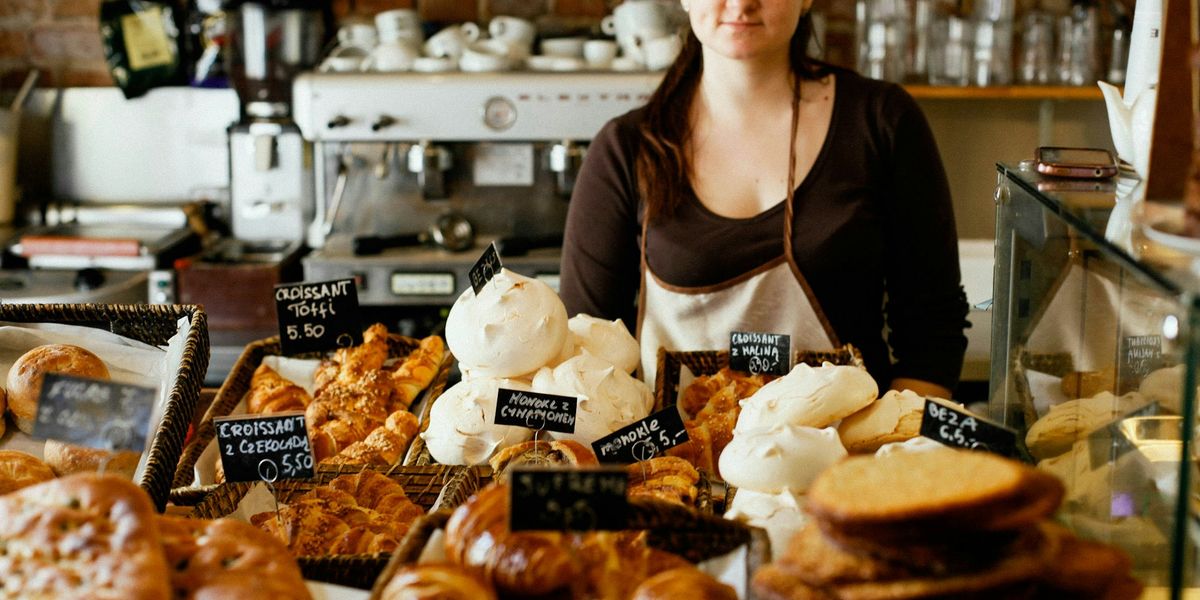A bakery owner behind a counter full of fresh bread