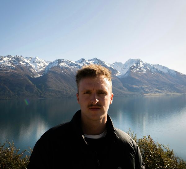 A man standing in front of a New Zealand lake and mountains