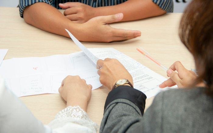 Two people reviewing loan documents at a meeting table