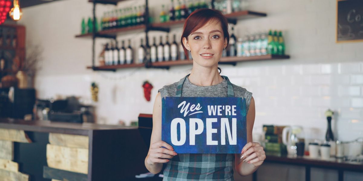 A smiling small business owner welcoming customers to her shop