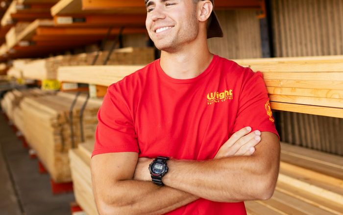 A smiling timber yard worker in a red shirt