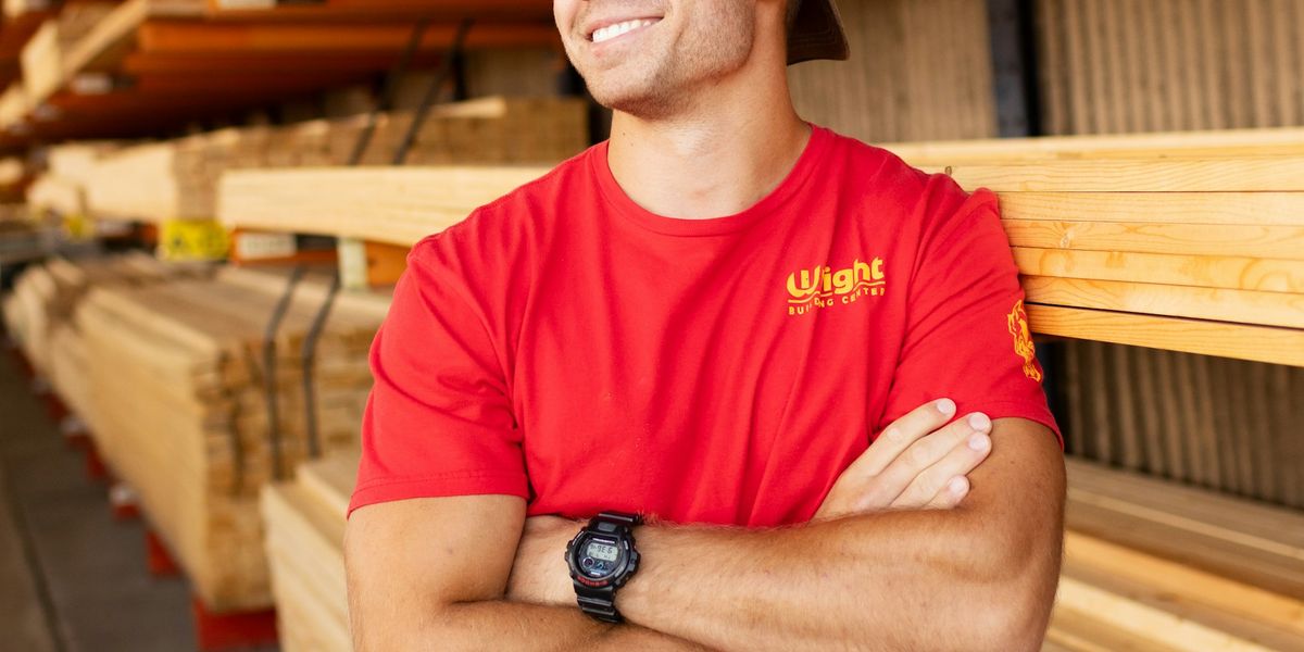 A smiling timber yard worker in a red shirt