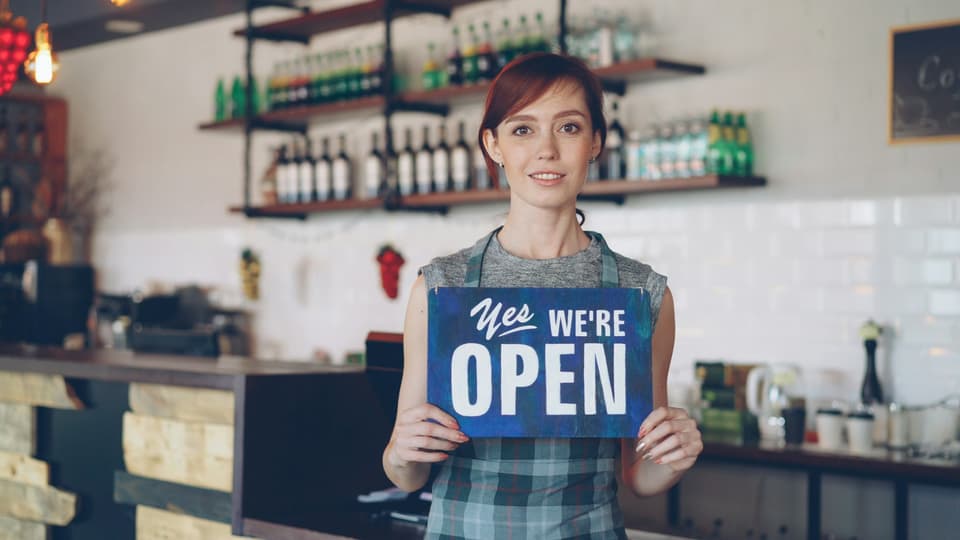 A smiling small business owner welcoming customers to her shop