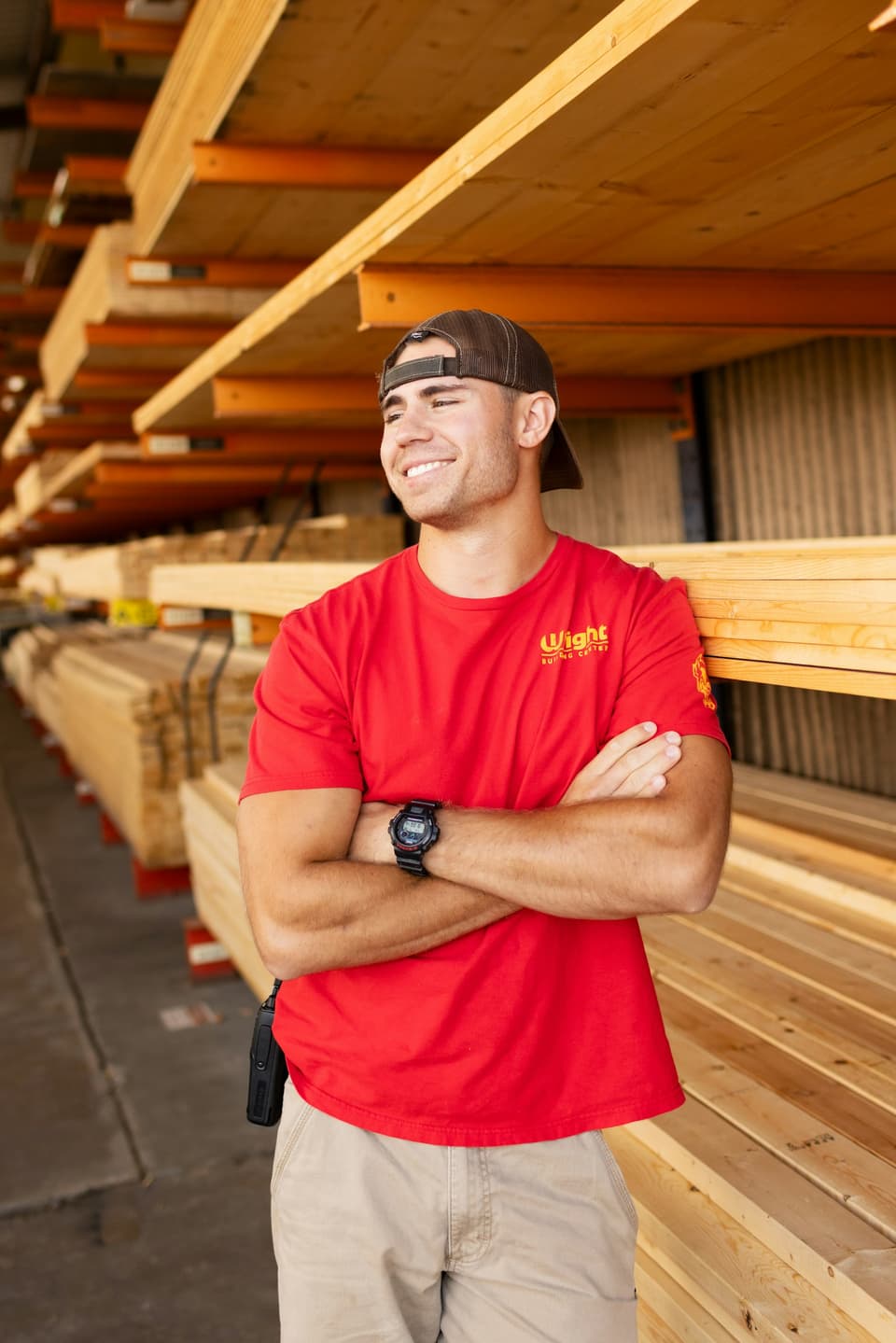 A smiling timber yard worker in a red shirt